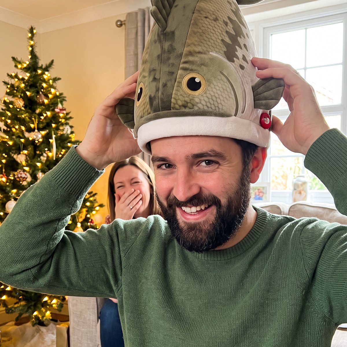 Young man trying on a Hawg Hat by the Christmas tree